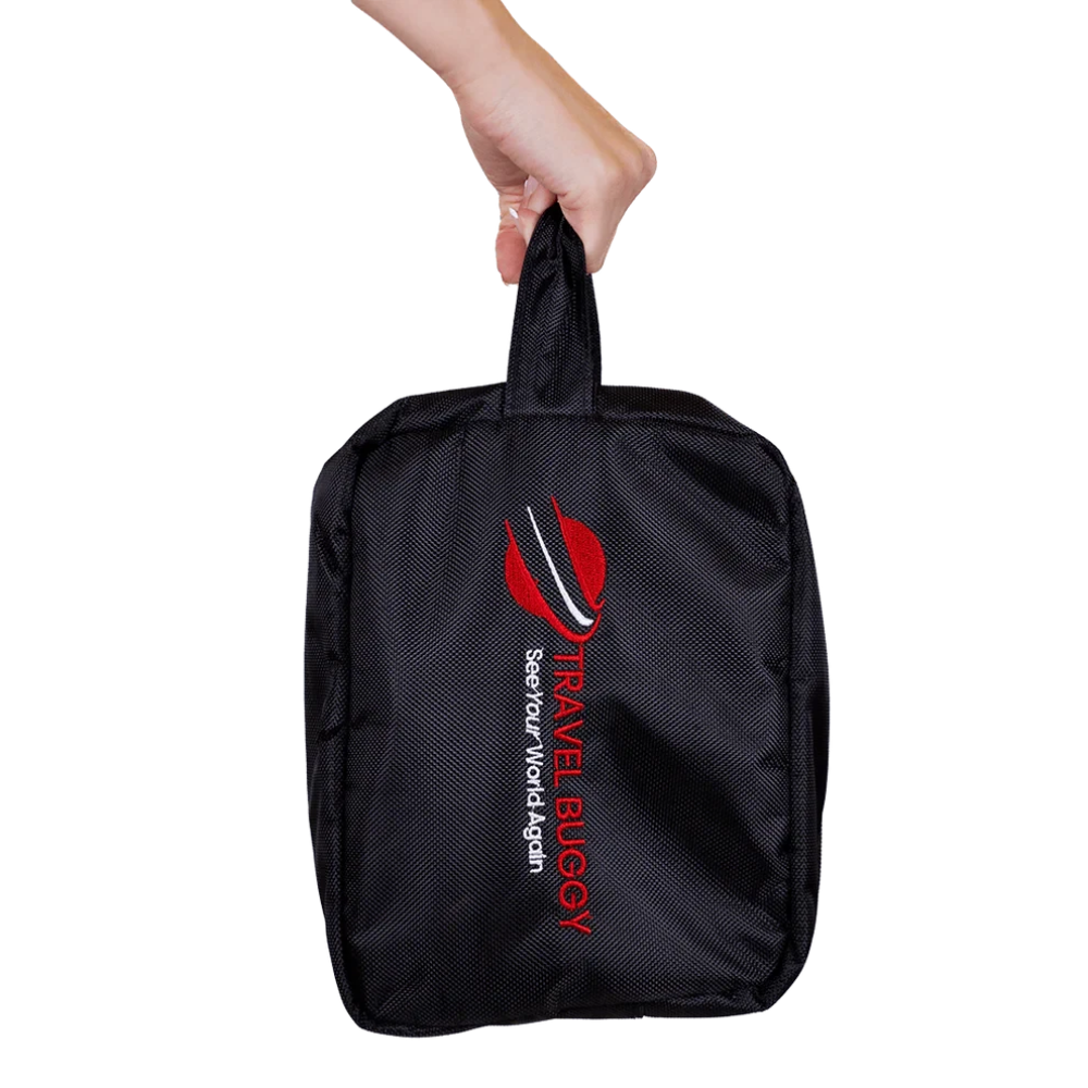 Person holding the lightweight Travel Buggy AEROLUX battery and joystick carry-on bag by its top handle.